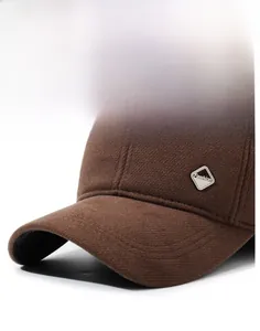 Detailed close-up of a brown wool baseball cap featuring a decorative silver metal logo