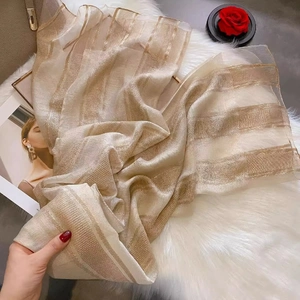 Detail of silk wool scarf with gold stripes on white faux fur and roses background