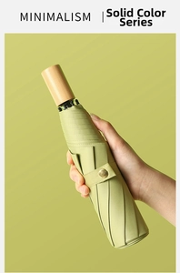 Minimalist green folding umbrella detail showing natural wood handle and fine fabric texture