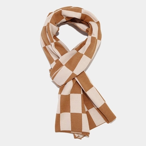 Gros plan sur le motif à damier caramel et crème de cette écharpe en maille douce