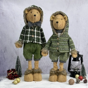 Pair of Christmas teddy bears in green knit outfits standing in a snowy winter scene