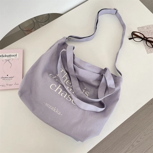 Close-up of light purple canvas tote bag with white artistic lettering and soft lighting