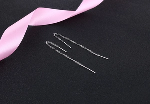 Detail view of long S925 silver threader earrings with sleek metal bars on black background