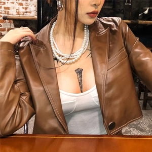Detail of a vintage multilayer pearl necklace on a model wearing a brown leather jacket