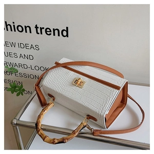 Detail of white faux-crocodile skin texture with natural bamboo handle and gold metal lock