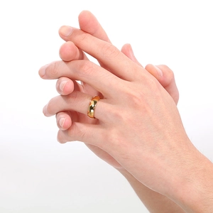 Top view of a gold minimalist wide band ring worn on a hand over a white background