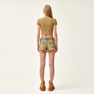 Woman in retro khaki crop top and mustard yellow frayed denim shorts with platform boots