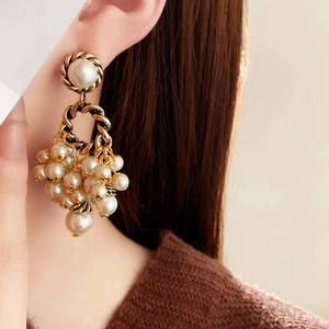Detailed close-up of vintage gold twist earrings with white pearl tassels on a model