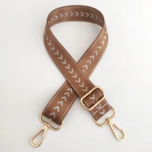 Detail of brown nylon strap with silver arrow embroidery and gold swivel metal hooks