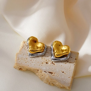 Détail de boucles d'oreilles cœur bicolores avec texture lave sur pierre et fond satiné