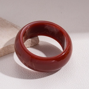 Detail of wide resin bangle with reddish-brown marble texture on stone display