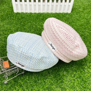 Dettaglio della trama in tweed e logo Mniya su baschi a scacchi azzurro e rosa confetto