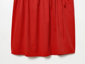 Gros plan détaillé de l'ourlet d'une robe rouge en coton avec des coutures de précision