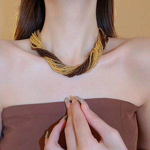 Dettaglio di collana bohémien multistrato con perline di precisione oro e marroni