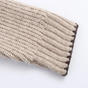 Gros plan du pull en maille beige montrant la texture et le bord contrasté marron