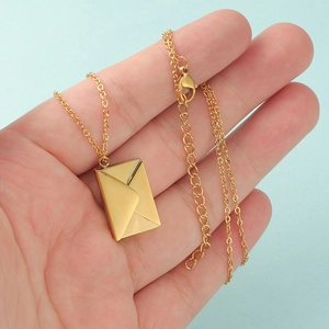 Handheld gold envelope pendant necklace with adjustable chain on a light blue background