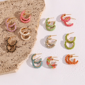 Detail showing C-shaped gold-plated hoop earrings with colorful checkered enamel patterns