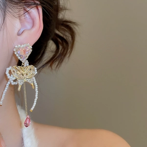 Detail of pink heart crystal and butterfly fringe tassel earrings on a model