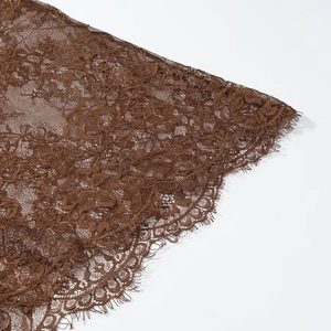 Close-up of brown lace fabric featuring intricate floral patterns and eyelash fringe detail