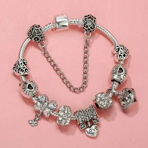 Macro detail of silver charm bracelet with heart locket, key pendants and Love engraving