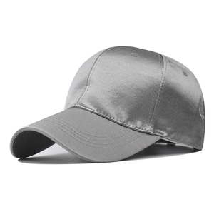 Detail of grey satin baseball cap showing glossy fabric texture and six-panel stitching
