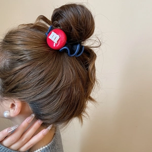 Détail d'un chouchou bleu avec charme m en résine rouge sur un chignon stylé