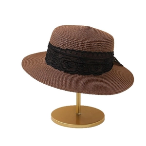 Flat top straw sun hat with black lace ribbon on a golden display stand for summer