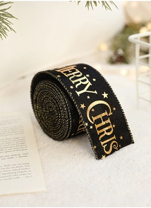 Detail of black Christmas ribbon with gold Merry Christmas text and stars in a festive roll