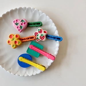 Close-up of colorful heart star and flower hair clips for girls in a white ceramic dish