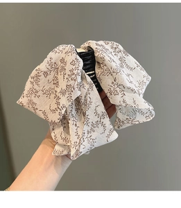 Détail de la pince à cheveux à nœud en mousseline fleurie montrant la texture du tissu