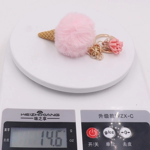 Close-up of cute plush pink ice cream keychain with gold ring and tassel detail