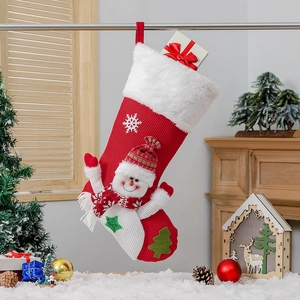 Chaussette de Noël en tricot avec bonhomme de neige et boîte cadeau devant la cheminée