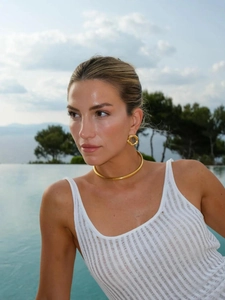 Detail of gold irregular earrings and chunky collar necklace on a model by the pool