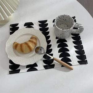 Detail of minimalist black and white geometric placemat with ceramic plate and cup