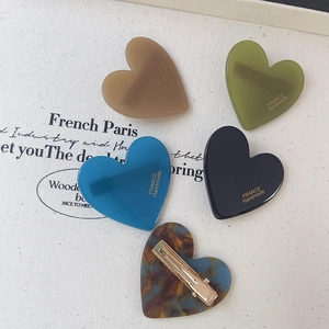 Détail de cinq pinces à cheveux en forme de cœur en acétate marron, vert, bleu, noir et écaille