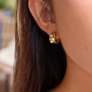 Close-up of model wearing polished 18K gold-plated stainless steel concave hoop earrings
