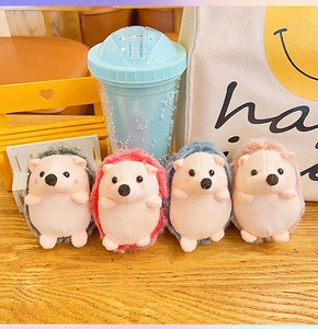 Detailed view of four colorful plush hedgehog keychains on a textured wooden table