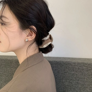 Detail shot of minimalist silver bean earrings worn by a model in a cozy, elegant style