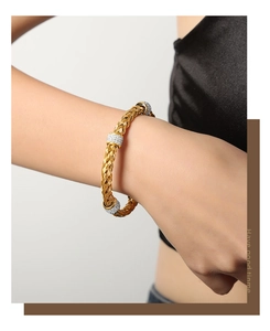 Detail of gold woven titanium steel bangle featuring three sparkling pave zircon sliders