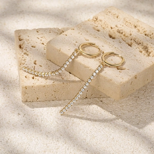 Close-up of S925 sterling silver gold fringe earrings with pavé zircon on travertine