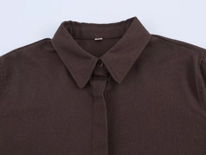 Detailed close-up of dark brown linen shirt collar with fabric texture and top button