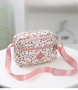 Detail of multi-pocket crossbody bag featuring pink polka dots and adjustable strap
