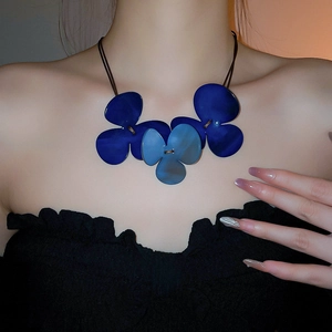 Close-up of three blue resin flower pendants on a vintage-style cord necklace