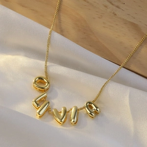 Macro shot of gold LOVE alphabet charm pendant necklace on white silk and wood