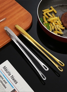 Détail de pinces de cuisine en acier inoxydable 304 argent et or sur un plan de cuisson