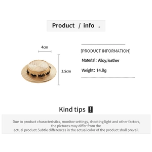 Detail view of a gold-toned straw hat brooch with black leather wrap and size measurements