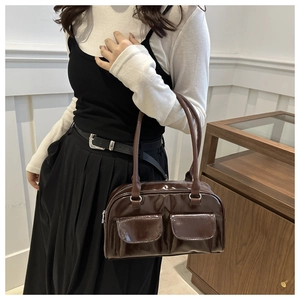 Detail of dark brown glossy patent leather shoulder bag with dual front flap pockets