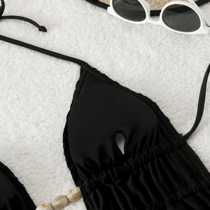 Détail du haut de bikini noir avec bonnets froncés et accents de perles blanches
