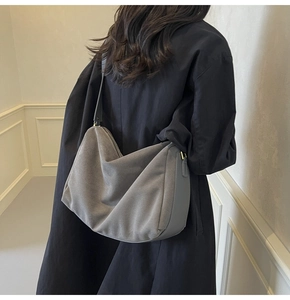 Detail of grey suede hobo bag on shoulder, minimalist vintage design with dark strap
