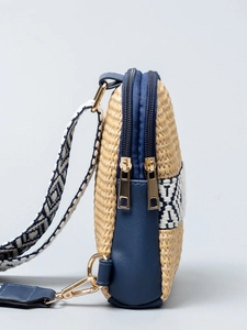 Crossbody straw bag with navy leather and jacquard strap shown in a side profile view